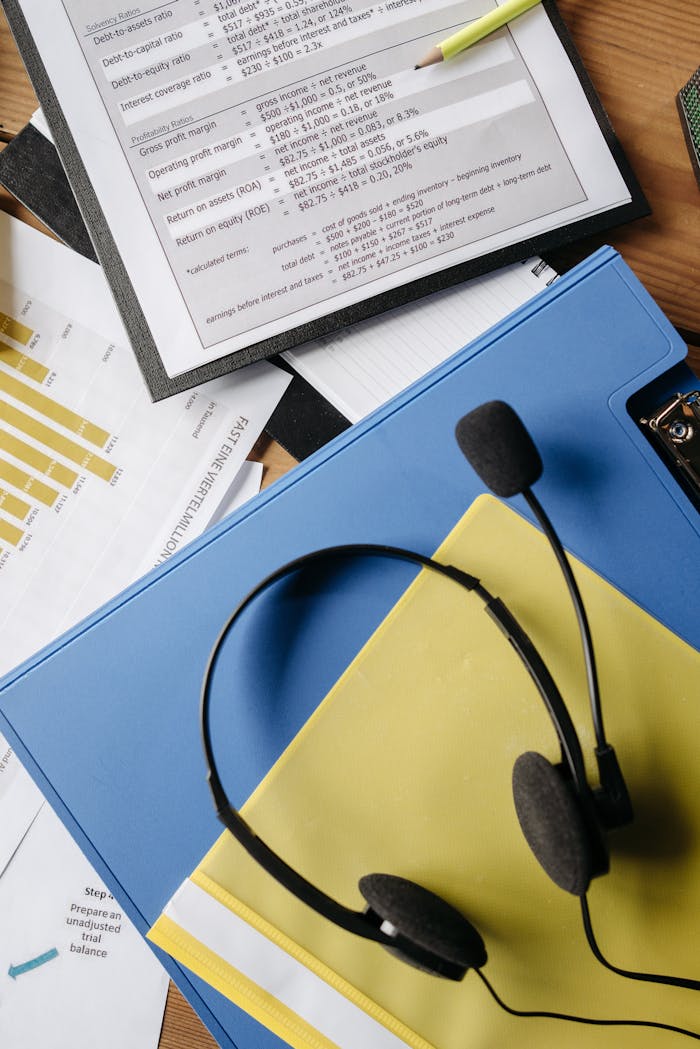 A neat flat lay of a call center desk setup featuring documents, charts, and a headset.