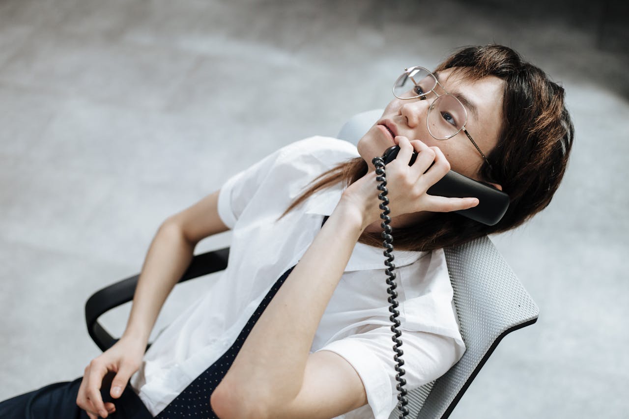 Young professional with glasses on a phone call in office setting.